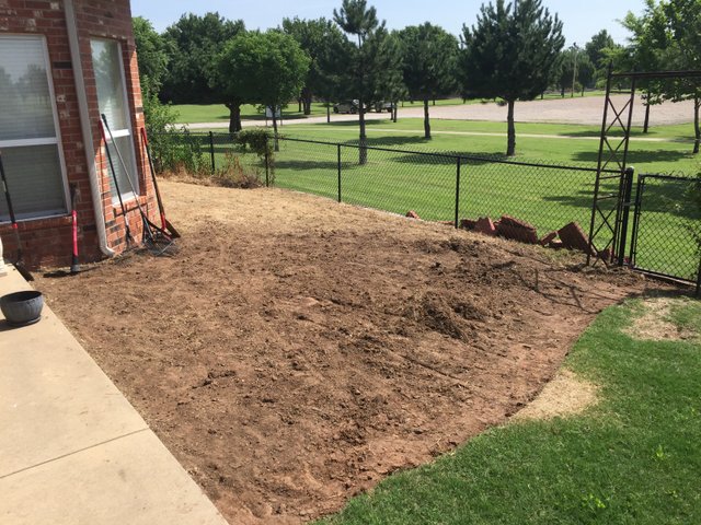 The same yard stripped down to bare dirt beside the patio, raked out and ready for the stone