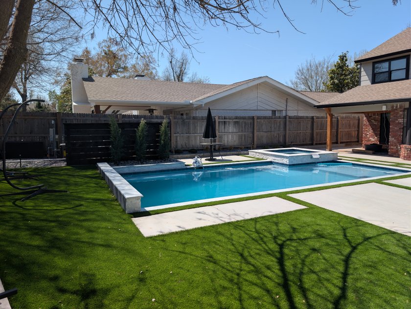 Finished backyard pool with a raised spa, concrete deck and artificial turf lawn