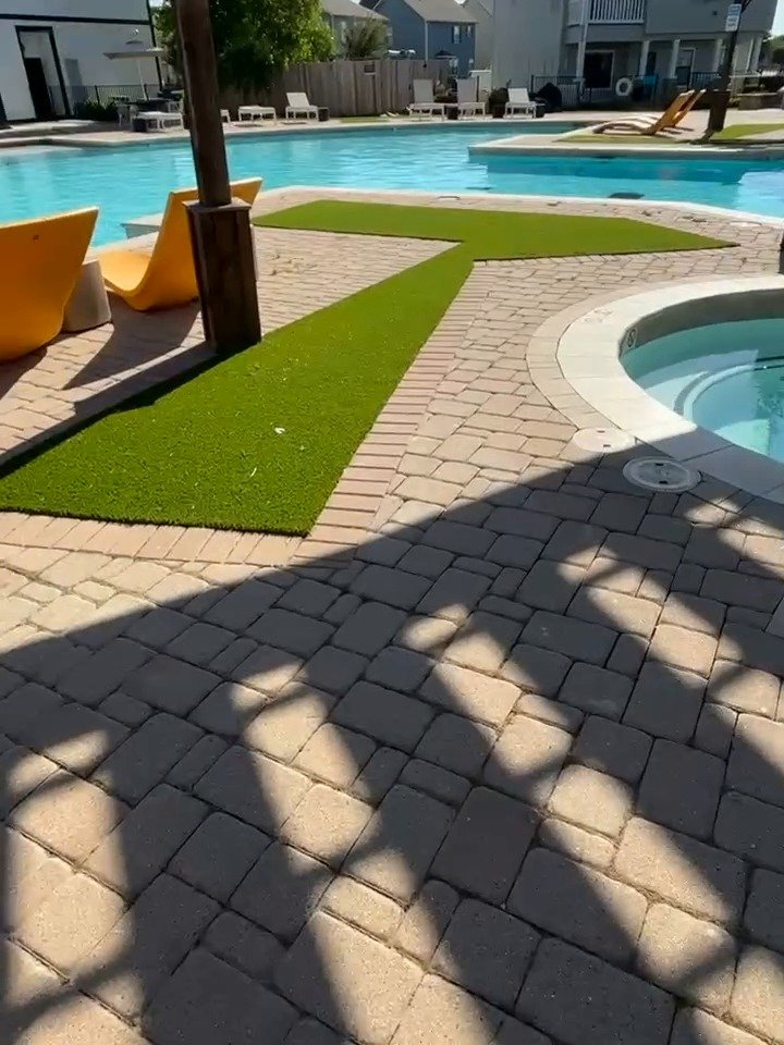 Artificial turf strips set into a paver pool deck at an apartment community