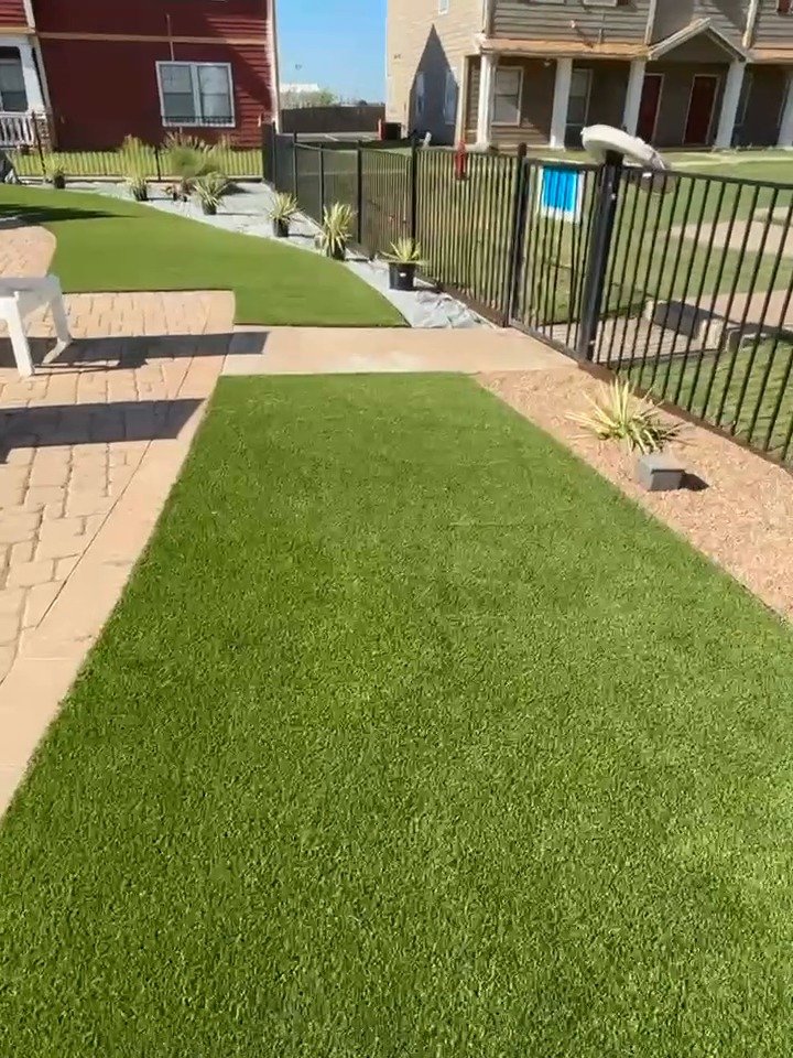 Artificial turf strip between a paver walkway and a gravel bed at a commercial property