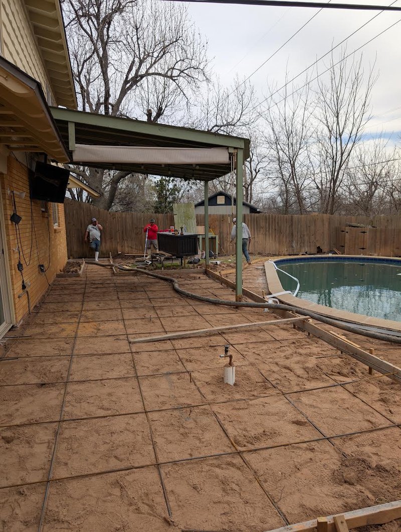 Crew setting forms and grading the base for a new concrete pool deck under a covered patio