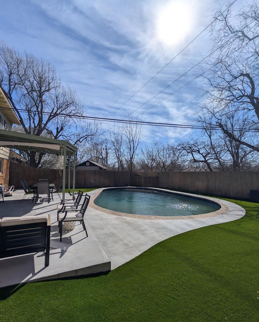 New concrete pool deck and patio curving into artificial turf in an Oklahoma City backyard