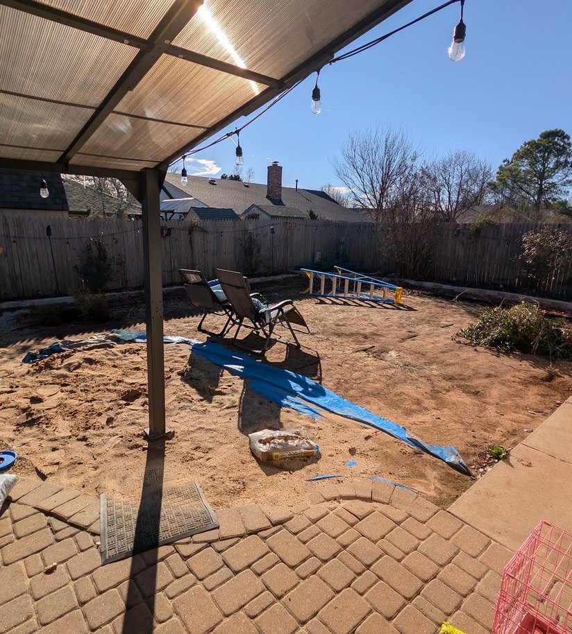 Before: bare dirt yard beside a paver patio under a covered pergola