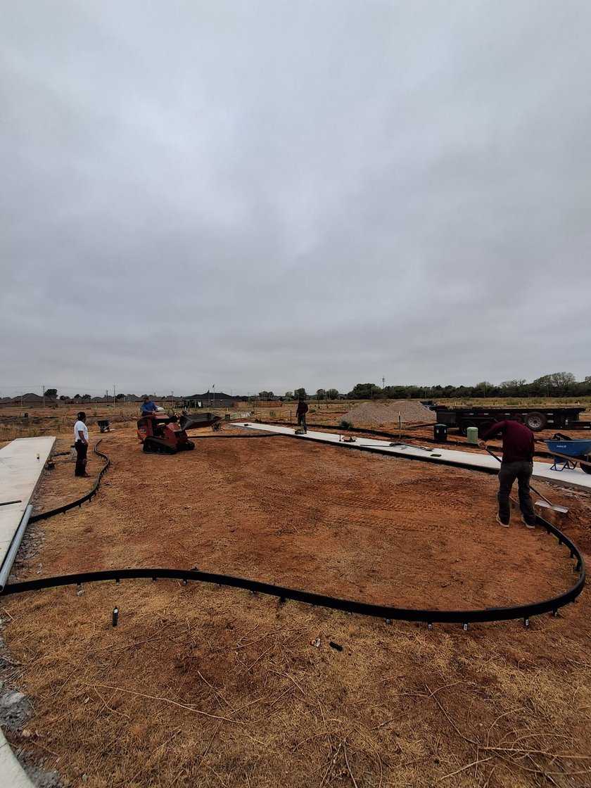 Crew setting black edging and grading red dirt before the turf base goes down