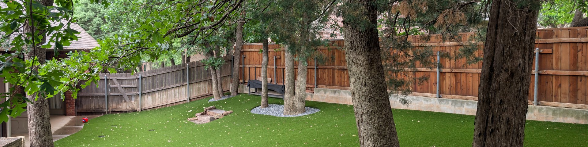 Pet turf installed around shade trees in a fenced Oklahoma City backyard