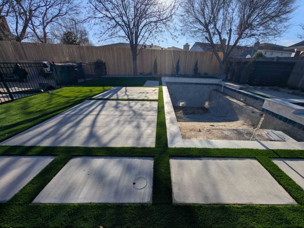 After: artificial turf strips installed between the concrete pavers around the same pool