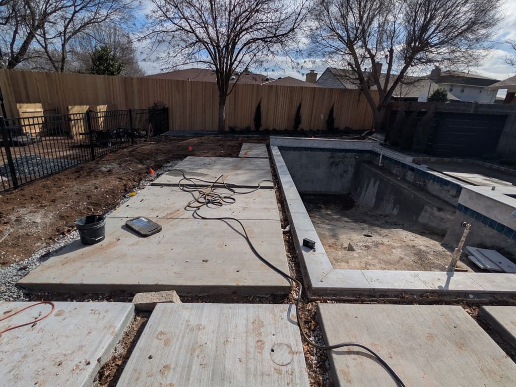 Before: large concrete pavers set on bare ground around a new pool shell