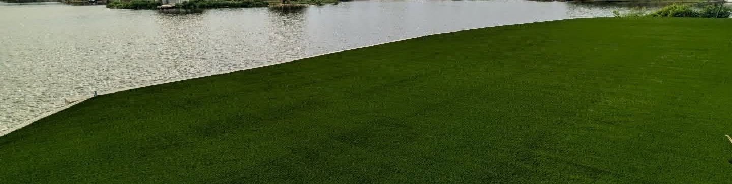 Artificial turf lawn running down to the shore of a lakefront backyard
